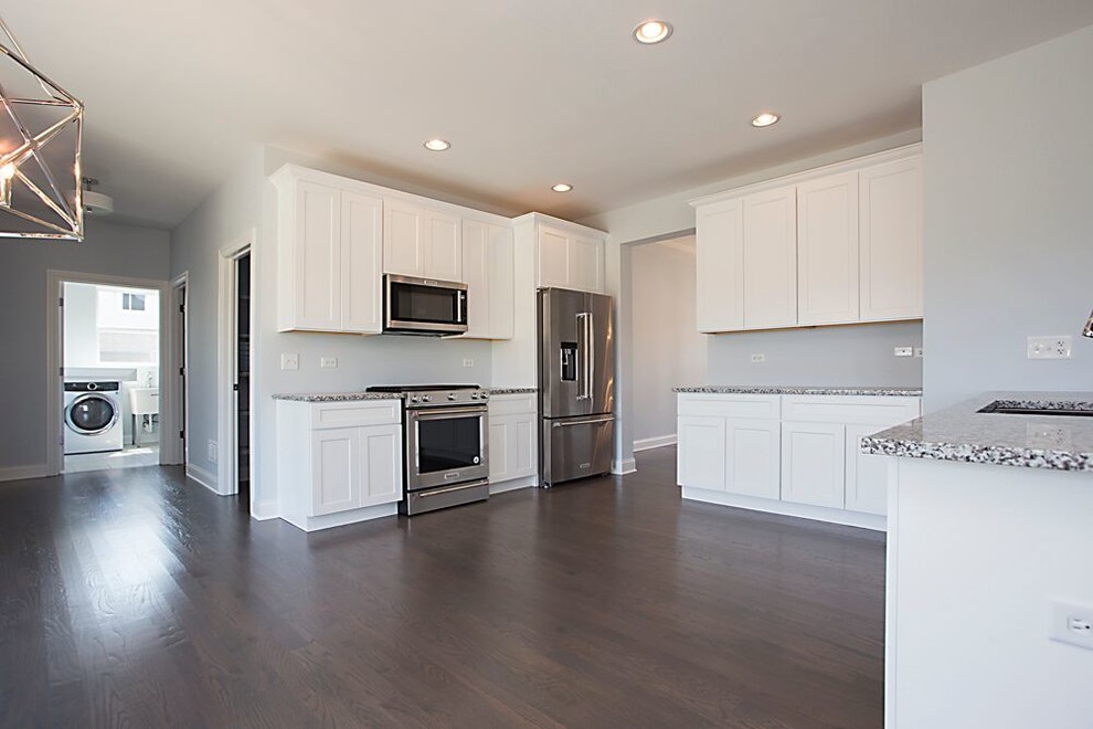 Kitchen - large transitional single-wall dark wood floor and brown floor kitchen idea in Chicago with an undermount sink, recessed-panel cabinets, white cabinets, granite countertops, stainless steel appliances and no island