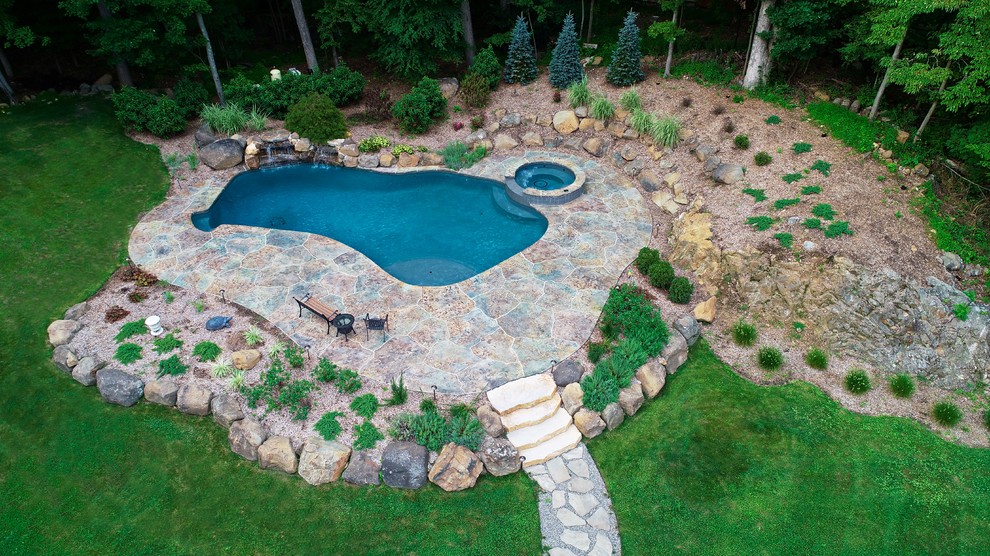 Design ideas for a country backyard custom-shaped natural pool in New York with stamped concrete.