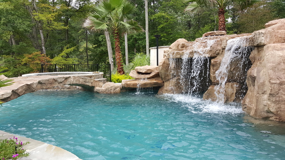 Inspiration for a large tropical backyard custom-shaped pool in Raleigh with a water slide and natural stone pavers.