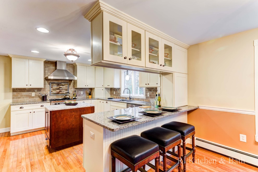 Inspiration for a large transitional u-shaped light wood floor eat-in kitchen remodel in Providence with an undermount sink, shaker cabinets, beige cabinets, granite countertops, brown backsplash, porcelain backsplash, stainless steel appliances and an island