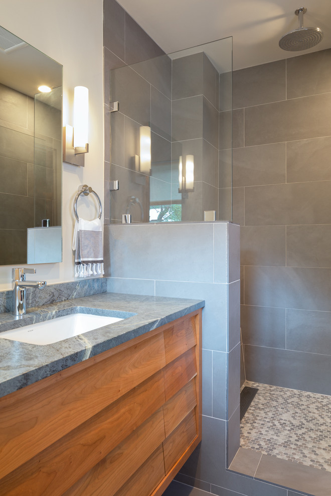 This is an example of a small midcentury bathroom in Austin with louvered cabinets, medium wood cabinets, an open shower, gray tile, porcelain floors, an undermount sink and soapstone benchtops.