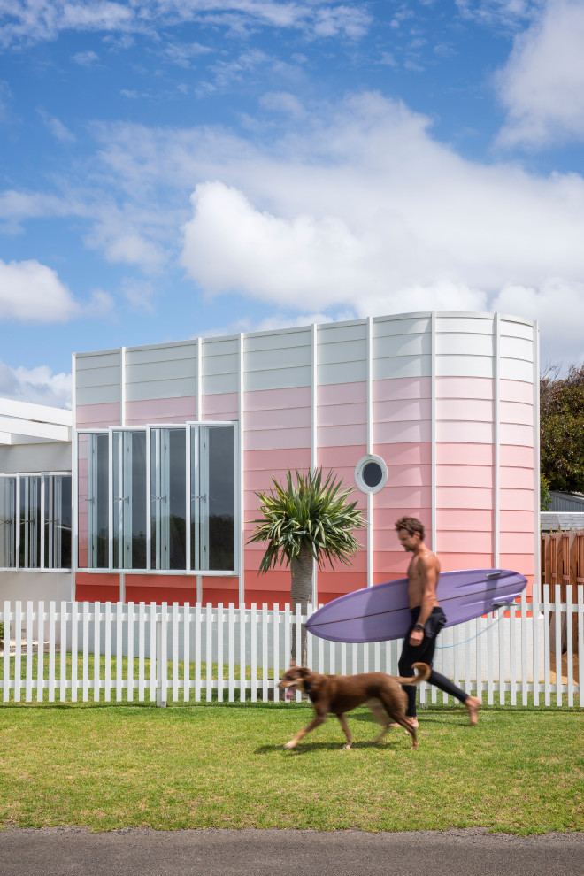 Design ideas for a beach style one-storey pink house exterior in Adelaide with mixed siding and a flat roof.