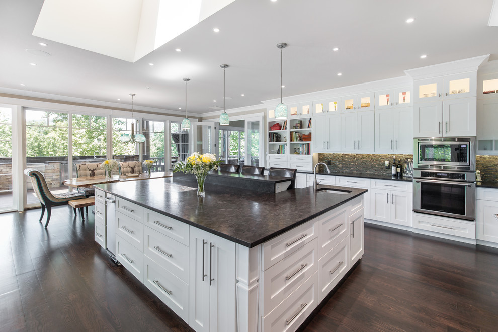 Large transitional u-shaped dark wood floor and brown floor eat-in kitchen photo with a double-bowl sink, shaker cabinets, white cabinets, concrete countertops, brown backsplash, matchstick tile backsplash, stainless steel appliances, an island and gray countertops