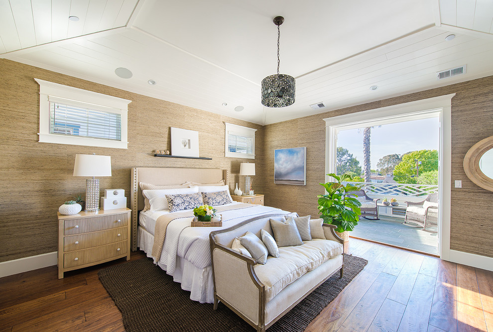This is an example of a beach style master bedroom in Los Angeles with brown walls and medium hardwood floors.