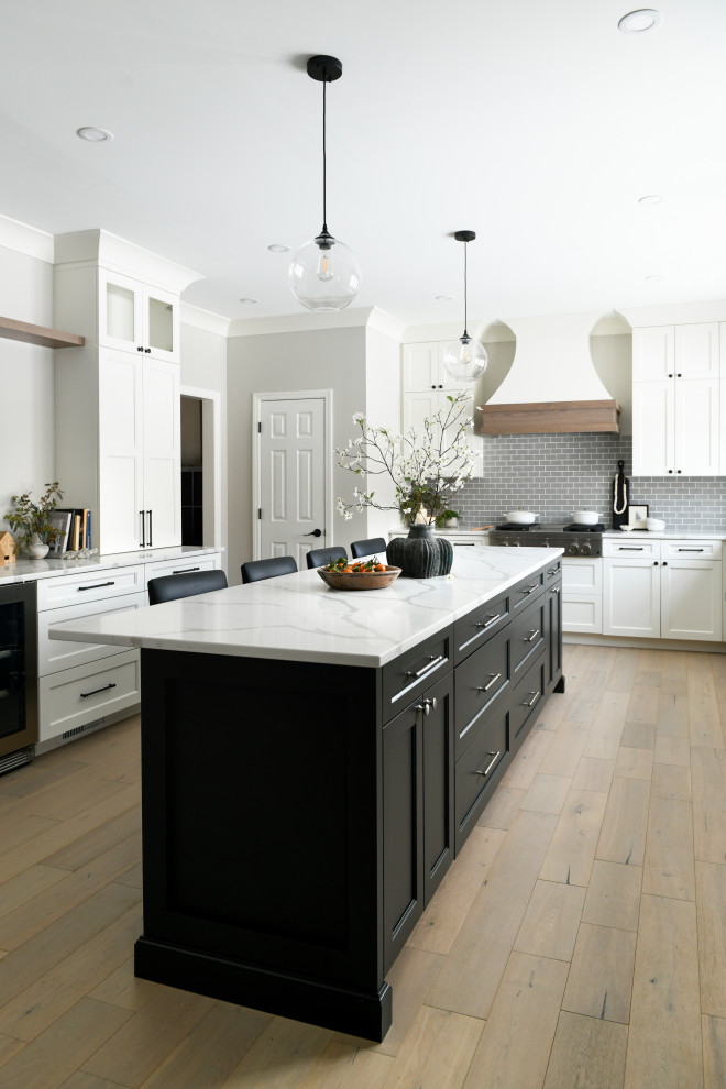 Large transitional brown floor eat-in kitchen photo in Other with an undermount sink, white cabinets, quartz countertops, gray backsplash, subway tile backsplash, stainless steel appliances, an island and white countertops