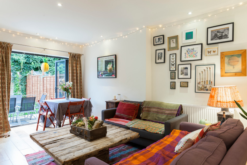 Photo of an eclectic living room in London with white walls and light hardwood floors.