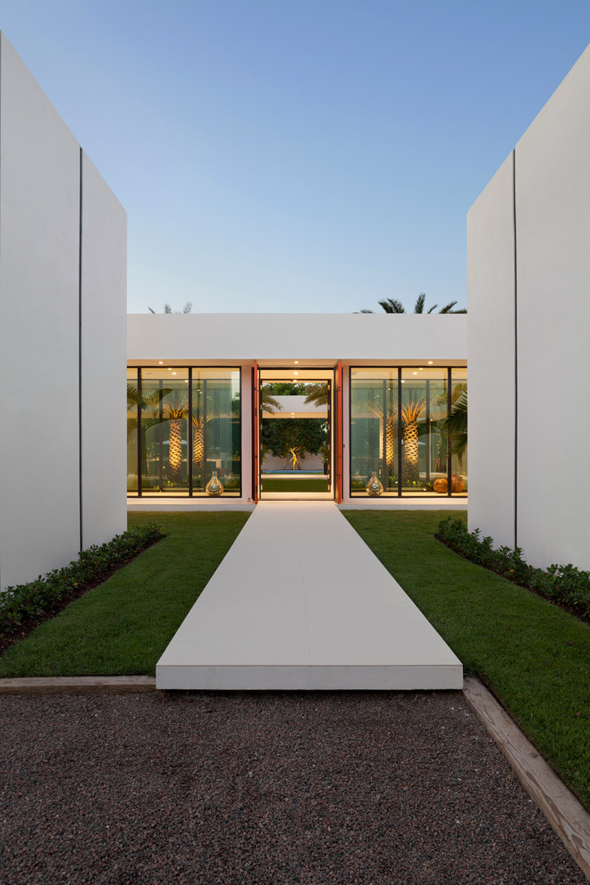 This is an example of an expansive contemporary one-storey white exterior in Miami with a flat roof.