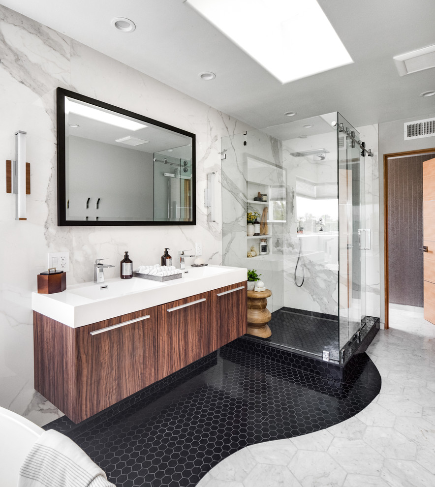 Mid-sized modern master bathroom in Orange County with flat-panel cabinets, medium wood cabinets, a freestanding tub, a corner shower, a two-piece toilet, white tile, stone slab, white walls, marble floors, an integrated sink, engineered quartz benchtops, white floor, a hinged shower door and white benchtops.