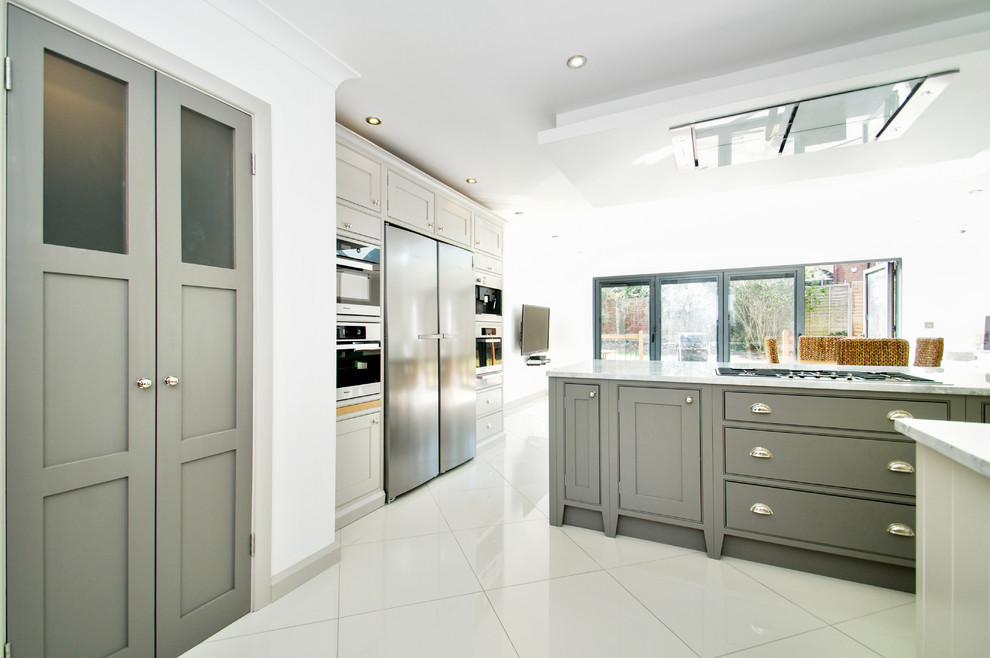 This is an example of a large traditional l-shaped eat-in kitchen in Sussex with a drop-in sink, beaded inset cabinets, grey cabinets, marble benchtops, stainless steel appliances, ceramic floors and a peninsula.