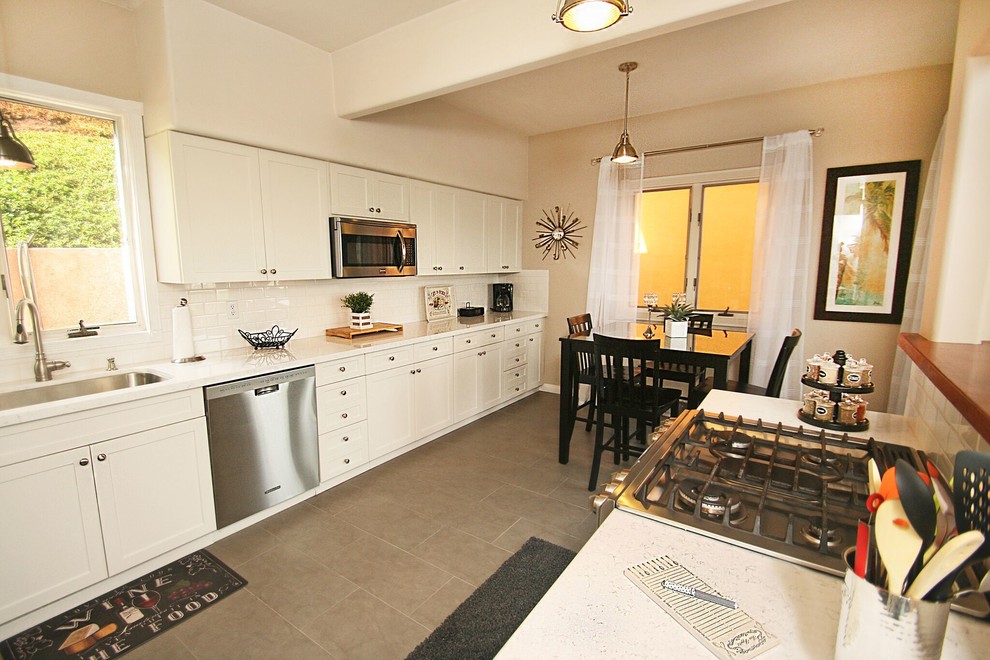 Eat-in kitchen - transitional galley eat-in kitchen idea in Orange County with a single-bowl sink, shaker cabinets, white cabinets, white backsplash, subway tile backsplash and stainless steel appliances
