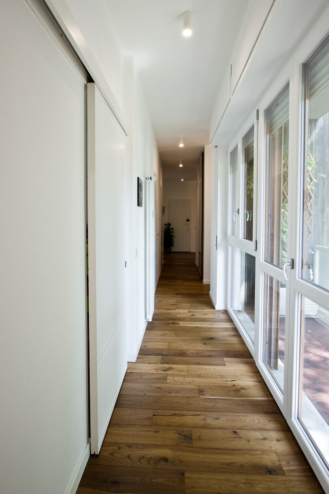 Photo of a large contemporary hallway in Milan with white walls and light hardwood floors.