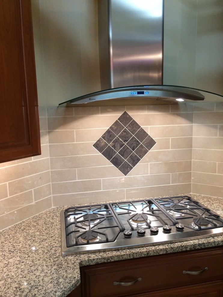 Mid-sized transitional l-shaped home design photo with recessed-panel cabinets, medium tone wood cabinets, granite countertops, beige backsplash, porcelain backsplash, stainless steel appliances and a peninsula