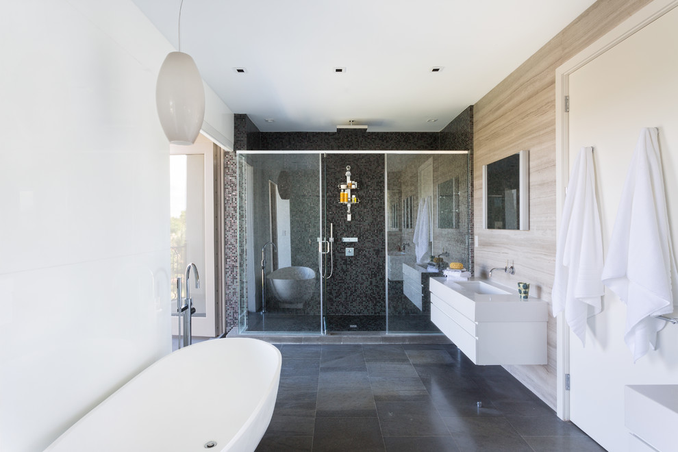 Photo of a large contemporary master bathroom in Miami with flat-panel cabinets, white cabinets, a freestanding tub, an alcove shower, mosaic tile, white walls, an integrated sink and solid surface benchtops.