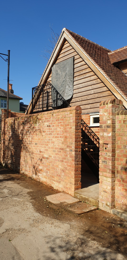 This is an example of a mid-sized traditional metal straight staircase in Berkshire with open risers, metal railing and brick walls.