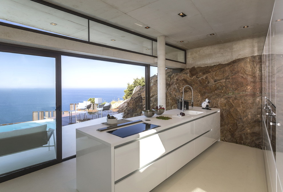 Inspiration for a mid-sized contemporary galley separate kitchen in Barcelona with an integrated sink, flat-panel cabinets, white cabinets, solid surface benchtops, stainless steel appliances and with island.