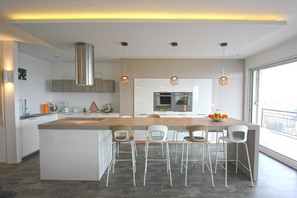 Photo of a mid-sized contemporary u-shaped eat-in kitchen in Lyon with white cabinets, white splashback, glass sheet splashback, stainless steel appliances, with island, flat-panel cabinets, an undermount sink, laminate benchtops, laminate floors, beige benchtop and grey floor.