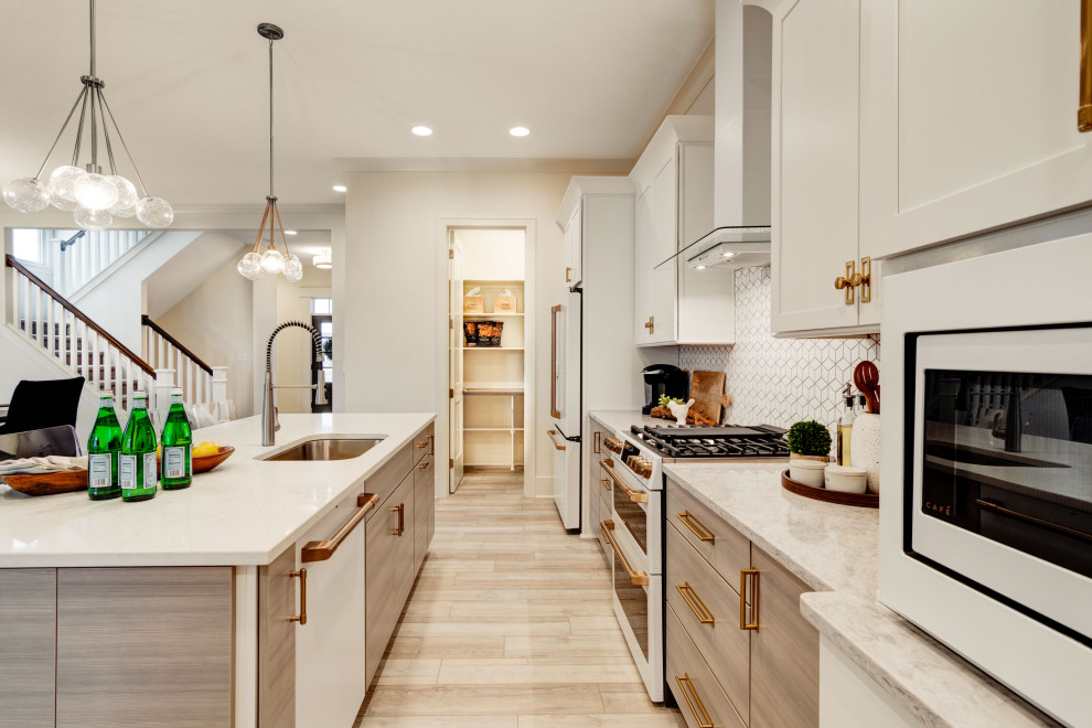 This is an example of a mid-sized contemporary single-wall kitchen pantry in Indianapolis with an undermount sink, shaker cabinets, white cabinets, granite benchtops, white splashback, ceramic splashback, white appliances, vinyl floors, with island, multi-coloured floor and white benchtop.