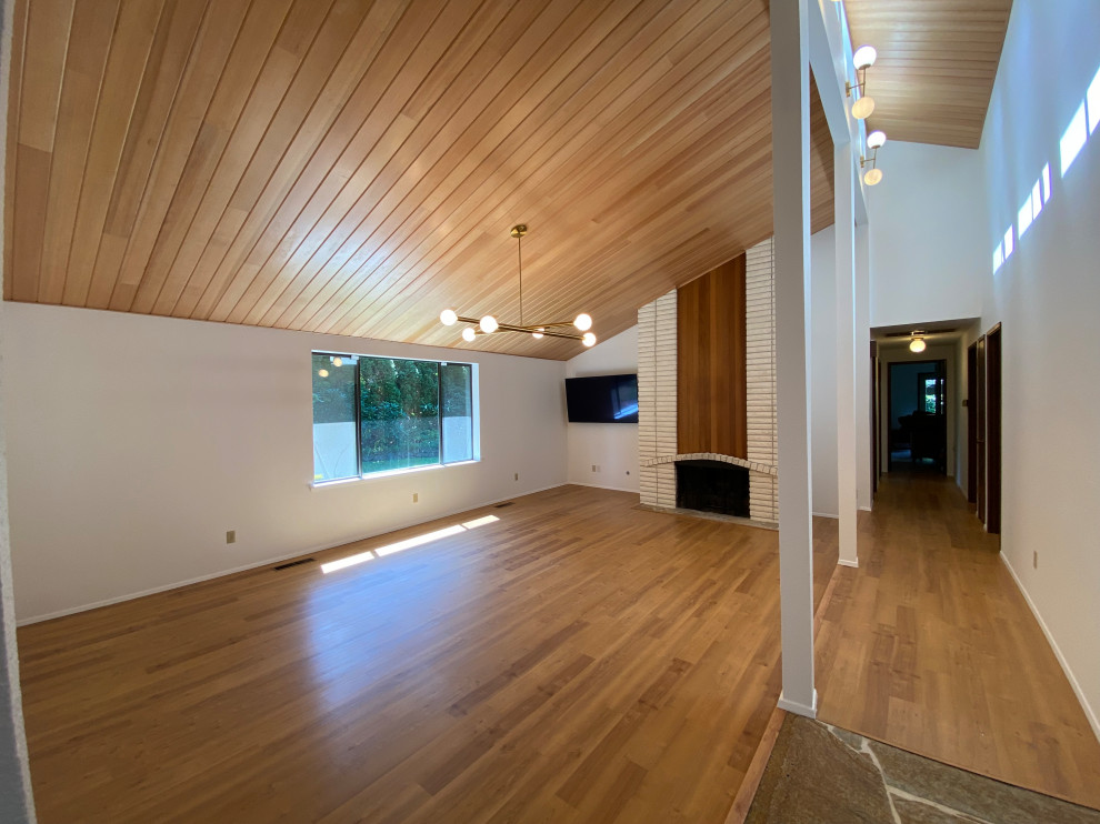 Family room - mid-sized mid-century modern light wood floor and wood ceiling family room idea in Seattle with white walls, a standard fireplace and a brick fireplace