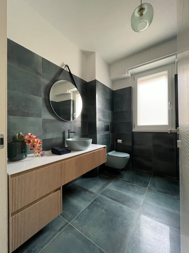 Inspiration for a large contemporary cloakroom in Rome with raised-panel cabinets, light wood cabinets, a wall mounted toilet, green tiles, porcelain tiles, porcelain flooring, a vessel sink, solid surface worktops, green floors, white worktops and a floating vanity unit.