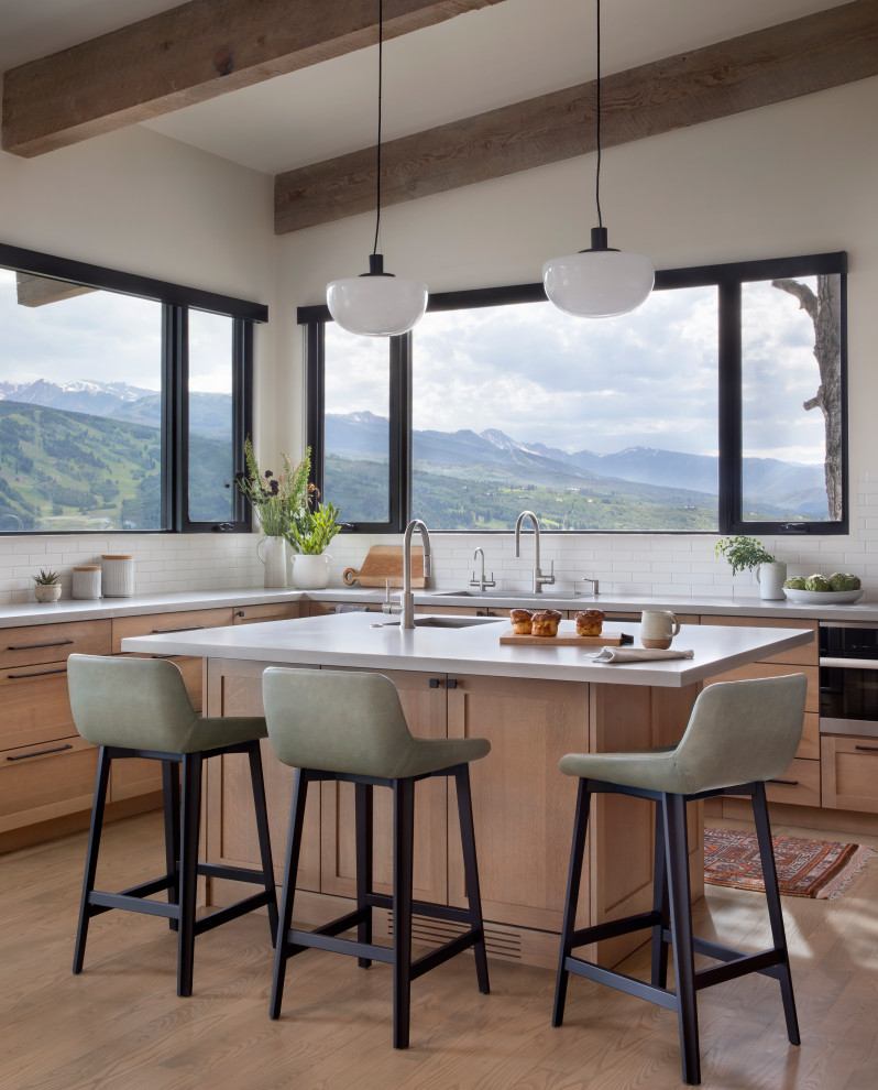 Example of a mid-sized mountain style u-shaped medium tone wood floor enclosed kitchen design in Denver with an undermount sink, shaker cabinets, medium tone wood cabinets, quartz countertops, white backsplash, quartz backsplash, stainless steel appliances and an island