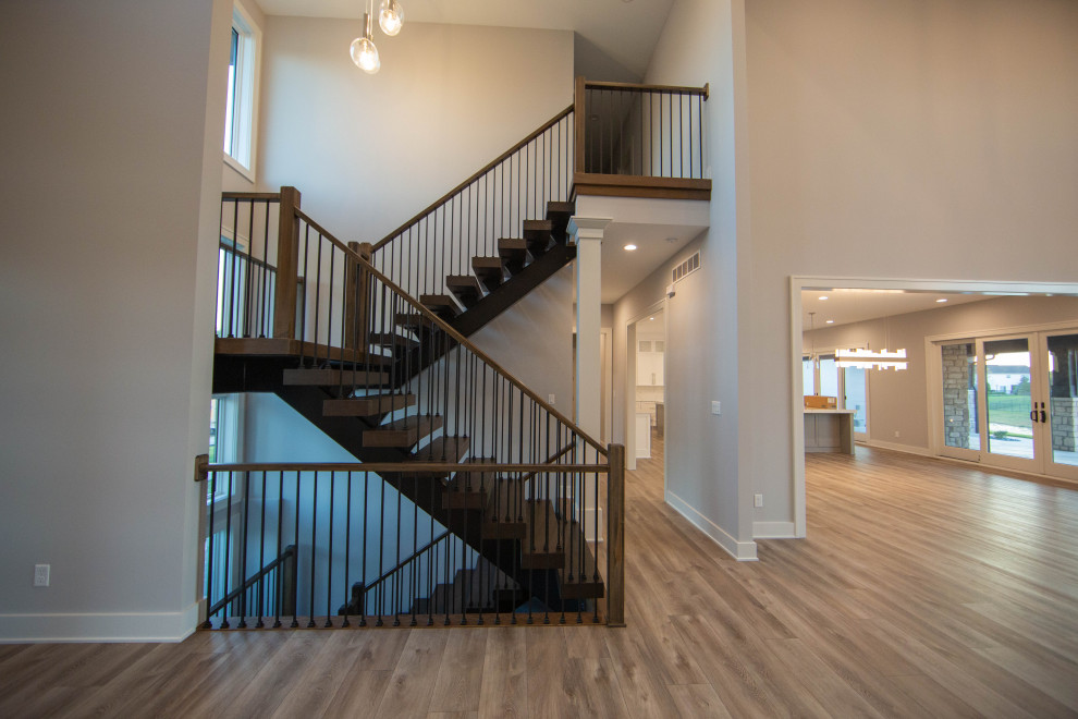 Large modern foyer in Indianapolis with beige walls, laminate floors, a double front door, a medium wood front door, brown floors and a vaulted ceiling.
