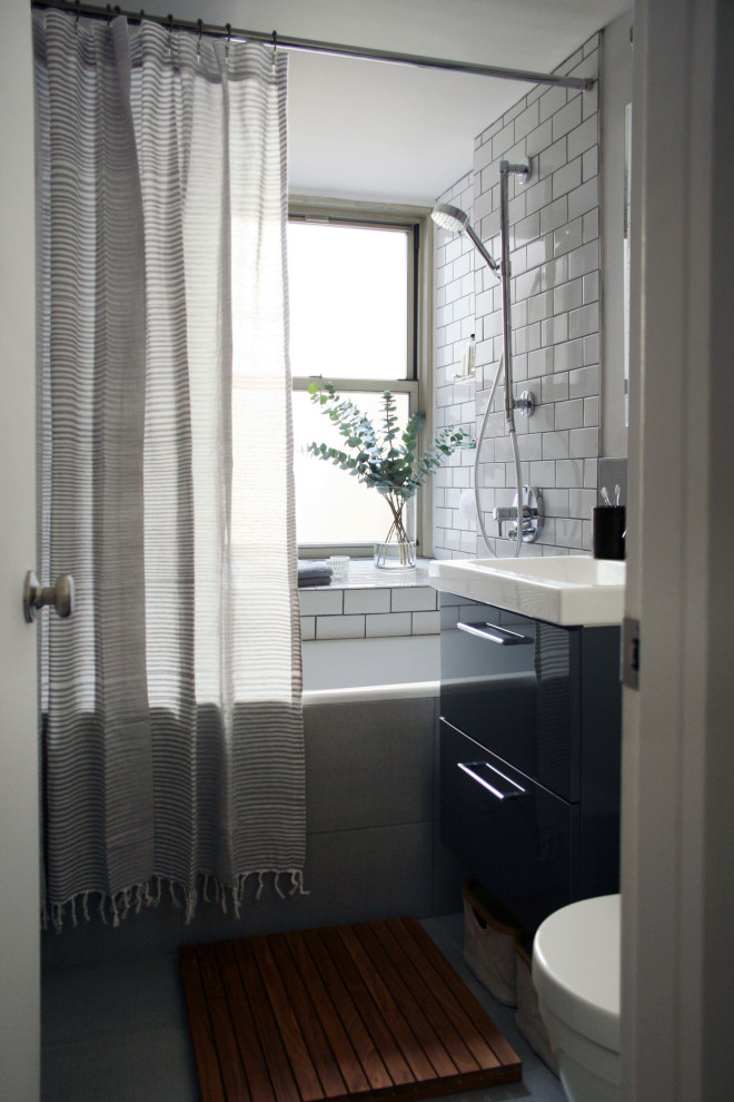 This is an example of a small midcentury bathroom in New York with flat-panel cabinets, grey cabinets, a drop-in tub, a shower/bathtub combo, gray tile, ceramic tile, grey walls, ceramic floors, grey floor, a shower curtain, a single vanity and a floating vanity.