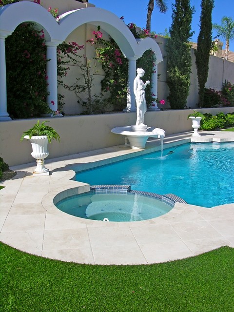 This is an example of a mid-sized mediterranean backyard custom-shaped natural pool in Phoenix with tile and a hot tub.