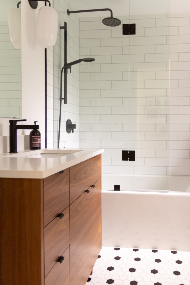 Idéer för ett litet 60 tals vit badrum med dusch, med släta luckor, skåp i mellenmörkt trä, ett badkar i en alkov, en dusch/badkar-kombination, en toalettstol med hel cisternkåpa, vit kakel, keramikplattor, vita väggar, klinkergolv i keramik, ett undermonterad handfat, bänkskiva i kvartsit, vitt golv och dusch med gångjärnsdörr
