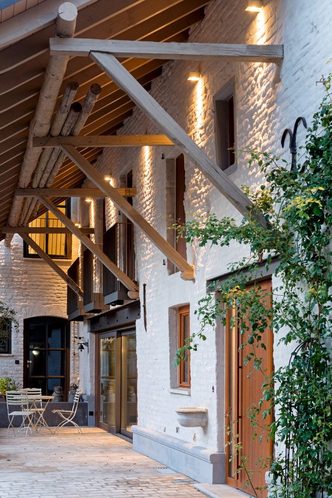 Inspiration for a large country courtyard patio in Cologne with brick pavers and a roof extension.
