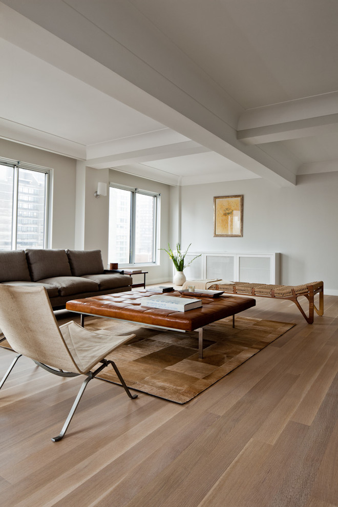 This is an example of a transitional living room in New York with white walls, medium hardwood floors and brown floor.
