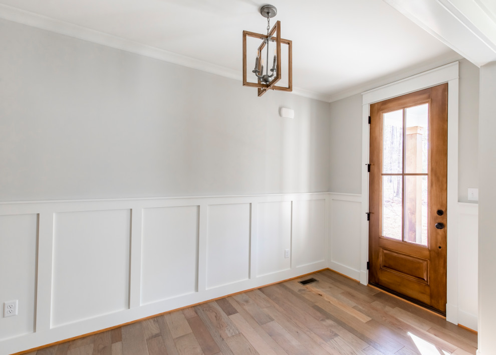 Landhausstil Foyer mit beiger Wandfarbe, hellem Holzboden, Einzeltür, brauner Haustür, braunem Boden und vertäfelten Wänden in Richmond