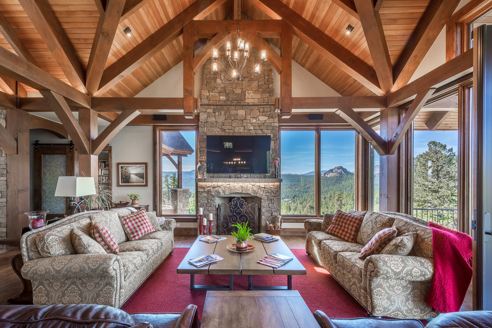 This is an example of a country family room in Denver with a standard fireplace, a stone fireplace surround and a wall-mounted tv.