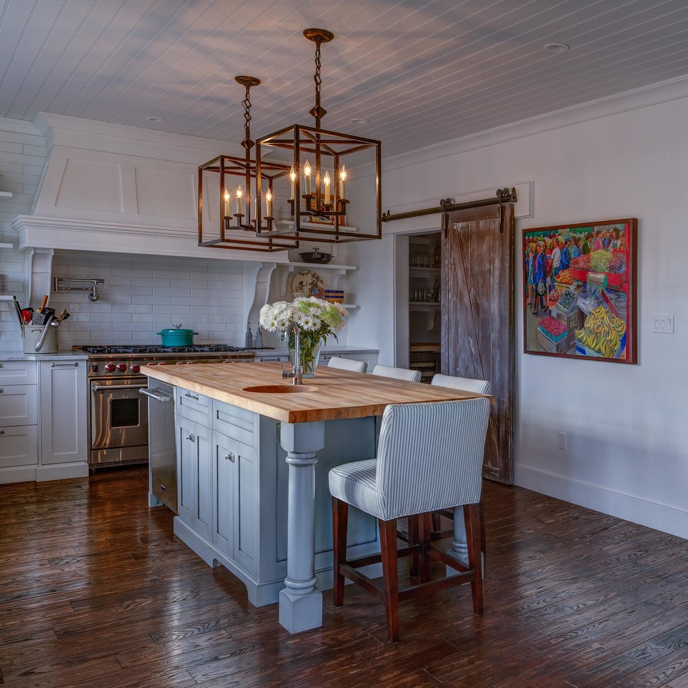Inspiration for a mid-sized transitional l-shaped dark wood floor and brown floor eat-in kitchen remodel with an undermount sink, shaker cabinets, white cabinets, wood countertops, white backsplash, subway tile backsplash, stainless steel appliances and an island