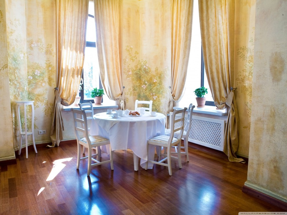 Photo of a mid-sized dining room in Miami with yellow walls, medium hardwood floors, no fireplace and a wood fireplace surround.