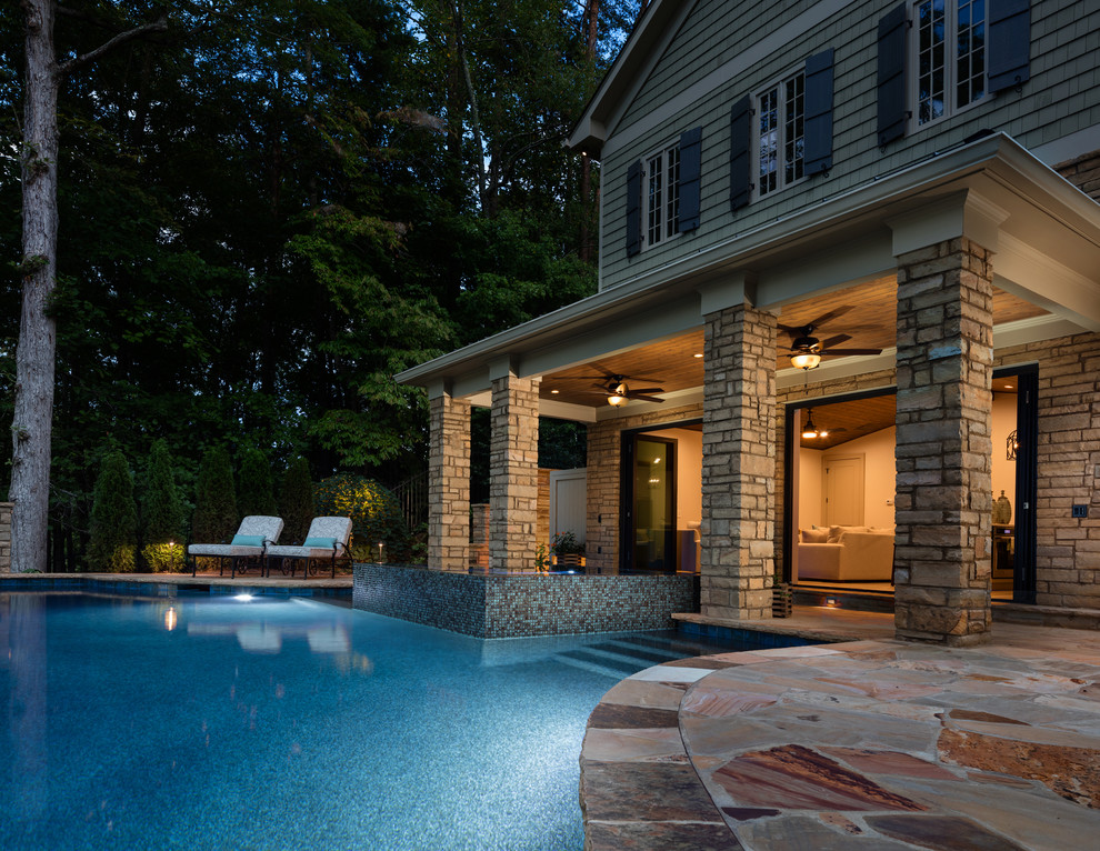 Photo of an expansive traditional backyard custom-shaped infinity pool in Atlanta with a pool house and brick pavers.