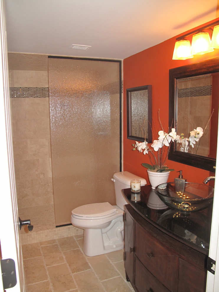 Inspiration for a mid-sized tropical 3/4 bathroom in Atlanta with flat-panel cabinets, dark wood cabinets, an alcove shower, a two-piece toilet, beige tile, orange walls, travertine floors, a vessel sink, brown floor and an open shower.