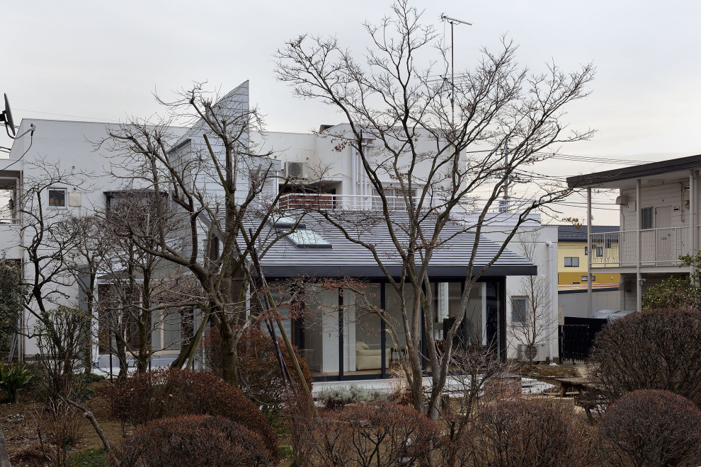Cette image montre une façade de maison blanche design en béton de taille moyenne et à un étage avec un toit en appentis, un toit en métal et un toit gris.