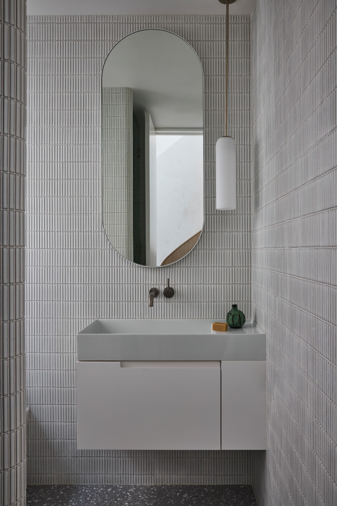 This is an example of a small contemporary kids bathroom in Sydney with flat-panel cabinets, white cabinets, gray tile, porcelain tile, grey walls, terrazzo floors, a wall-mount sink, granite benchtops, grey floor, grey benchtops, a single vanity and a floating vanity.