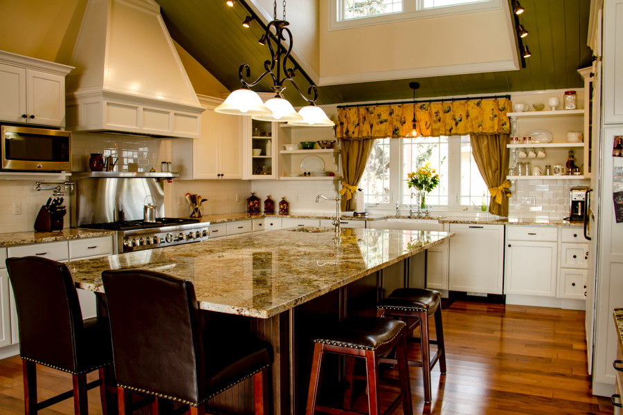 Large transitional u-shaped medium tone wood floor and brown floor open concept kitchen photo in Denver with a farmhouse sink, shaker cabinets, white cabinets, granite countertops, white backsplash, subway tile backsplash, stainless steel appliances and an island