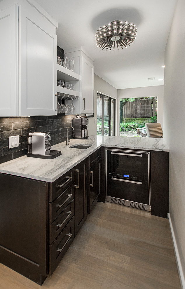 Photo of a small modern l-shaped wet bar in Dallas with an undermount sink, shaker cabinets, dark wood cabinets, marble benchtops, black splashback, stone tile splashback and light hardwood floors.