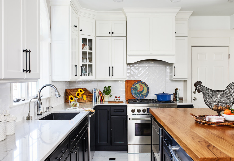 Photo of a mid-sized country l-shaped eat-in kitchen in Chicago with a farmhouse sink, shaker cabinets, white cabinets, quartz benchtops, white splashback, porcelain splashback, stainless steel appliances, porcelain floors, with island, white floor and white benchtop.