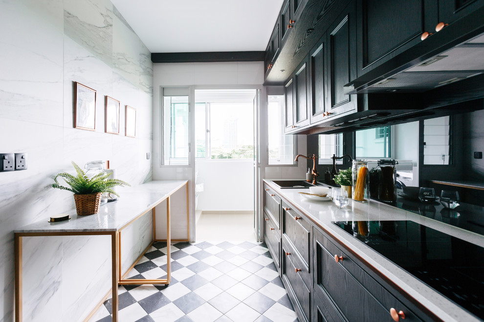 Inspiration for a transitional single-wall separate kitchen in Singapore with a drop-in sink, recessed-panel cabinets, black cabinets, black splashback, glass sheet splashback, black appliances, a peninsula, black floor and beige benchtop.