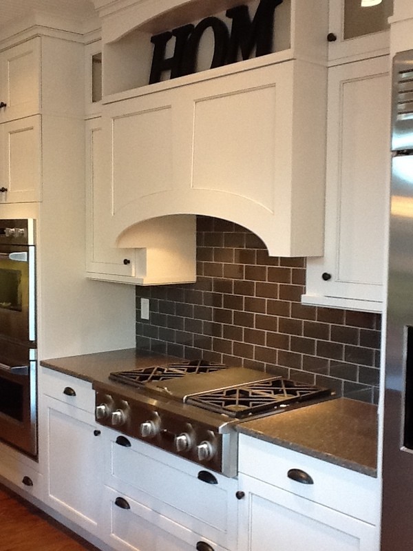 Photo of a large contemporary u-shaped eat-in kitchen in Cedar Rapids with a drop-in sink, shaker cabinets, white cabinets, granite benchtops, grey splashback, ceramic splashback, stainless steel appliances, medium hardwood floors and with island.