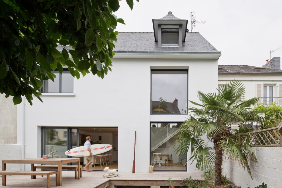 This is an example of a mid-sized beach style two-storey white townhouse exterior in Rennes with a gable roof and a shingle roof.