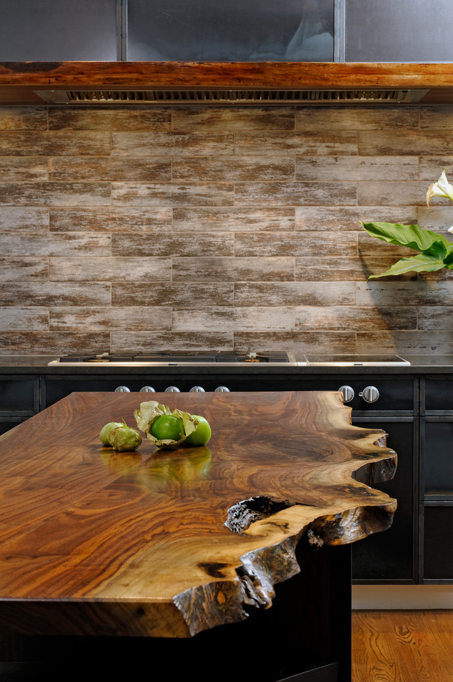 Eat-in kitchen - mid-sized transitional u-shaped medium tone wood floor and brown floor eat-in kitchen idea in DC Metro with black cabinets, wood countertops, brown backsplash, an island, stainless steel appliances, an undermount sink, flat-panel cabinets and porcelain backsplash