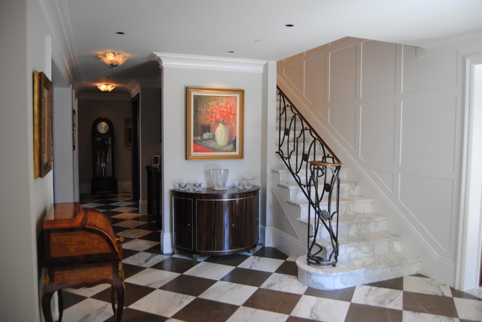This is an example of a mid-sized traditional entry hall in Orange County with white walls and marble floors.