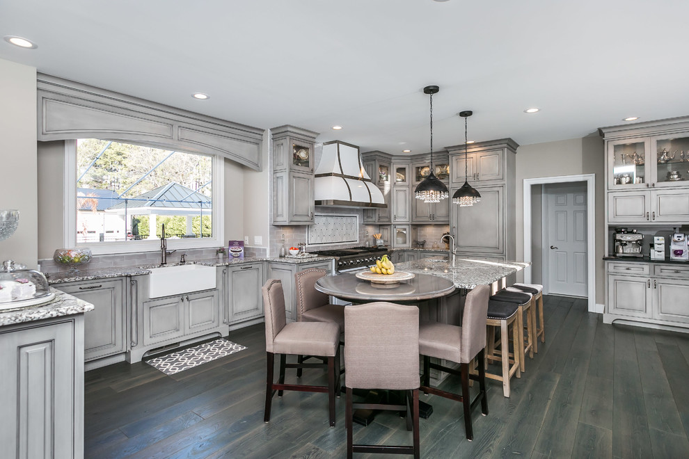 Photo of a large traditional u-shaped eat-in kitchen in Baltimore with a farmhouse sink, beaded inset cabinets, grey cabinets, granite benchtops, grey splashback, white appliances, medium hardwood floors, with island and grey floor.