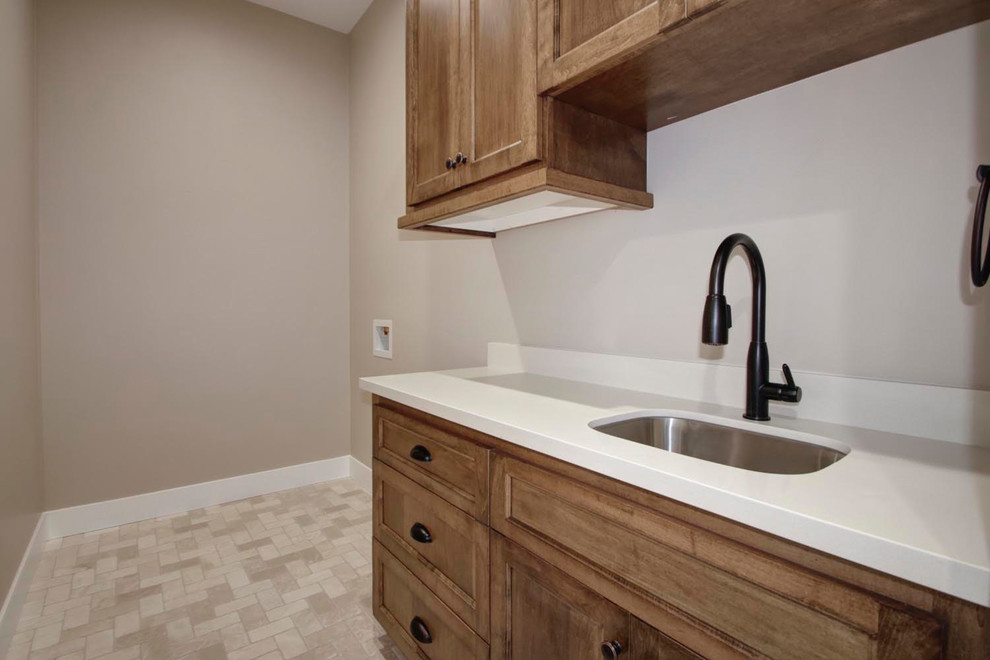 Inspiration for a small contemporary single-wall dedicated laundry room in Sacramento with a double-bowl sink, beaded inset cabinets, brown cabinets, limestone benchtops, grey walls, ceramic floors, a side-by-side washer and dryer, beige floor and white benchtop.