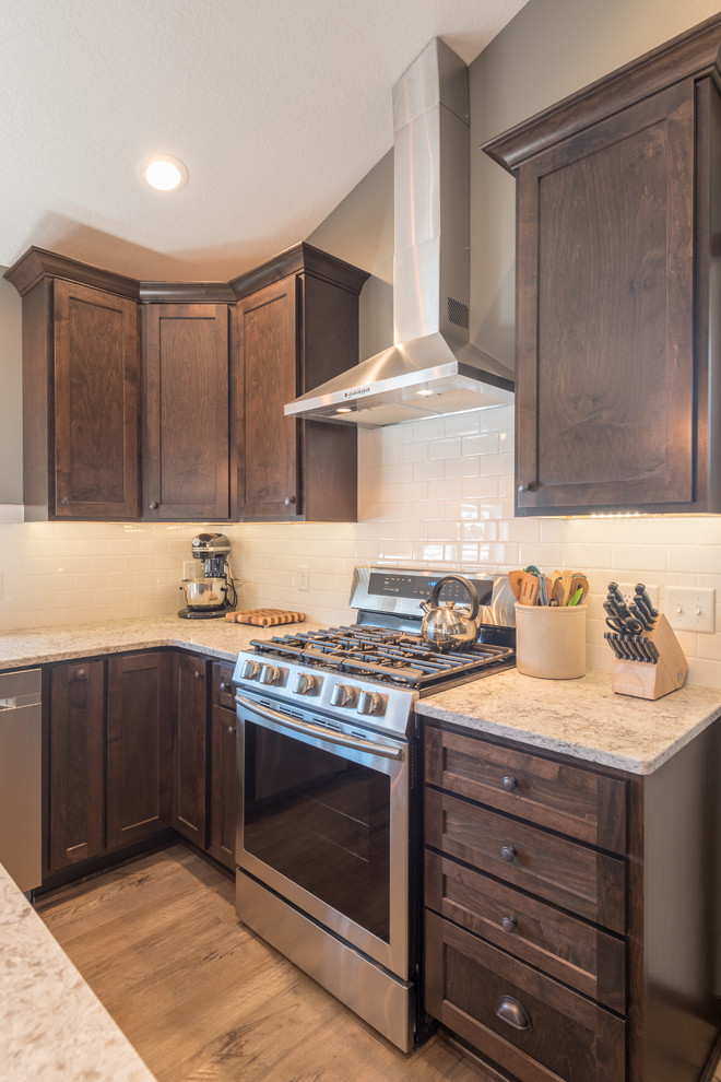 Large mountain style u-shaped dark wood floor and brown floor enclosed kitchen photo in Minneapolis with a double-bowl sink, shaker cabinets, dark wood cabinets, granite countertops, white backsplash, subway tile backsplash, stainless steel appliances and an island