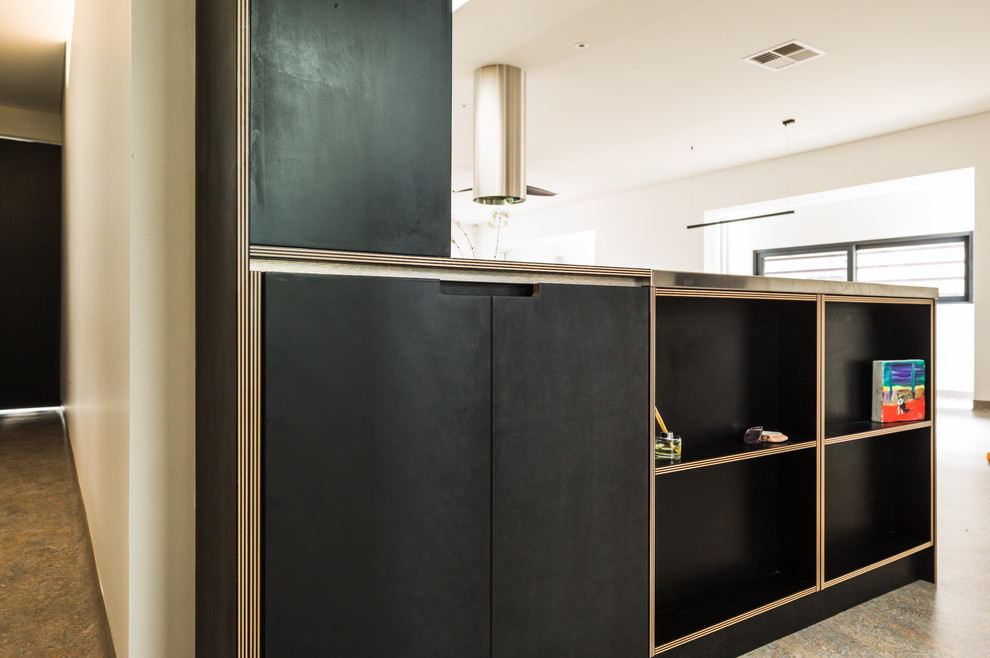 This is an example of a large contemporary l-shaped open plan kitchen in Perth with a double-bowl sink, flat-panel cabinets, black cabinets, orange splashback, stainless steel appliances, linoleum floors, with island and black benchtop.
